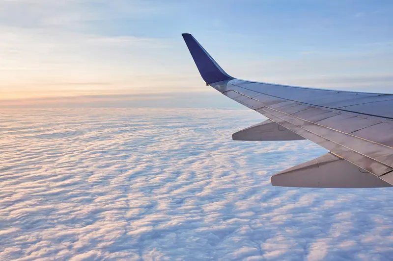 Aircraft wing above the clouds at sunrise